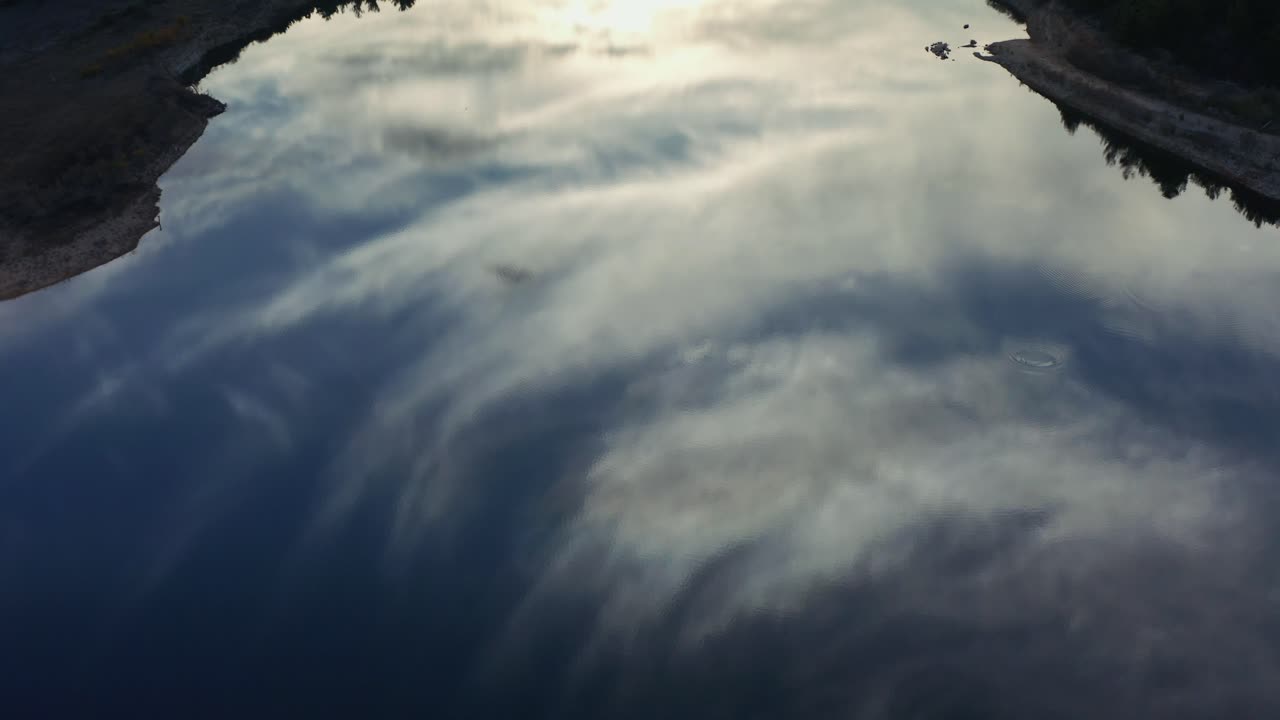 Aerial shot of the reflection of the sky over the calm lake