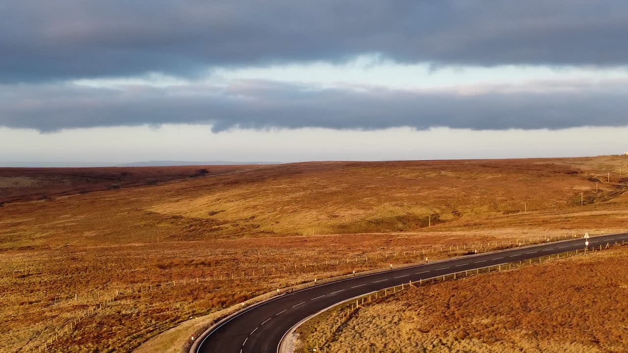 toma de drones del páramo del oeste de yorkshire y caminos sinuosos con la puesta de sol arrojando un sol dorado en las colinas