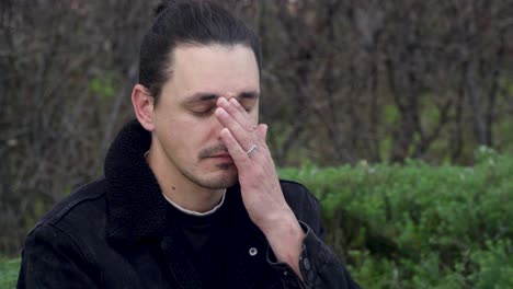 portrait of a young, sad and tired man wearing a black jacket and glasses