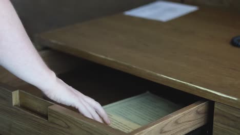 a person opens a drawer and retrieves a paper