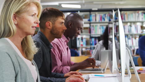 Group Of Mature College Students Working On Computers In Library