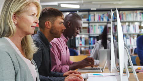 gruppe von reifen college-studenten, die an computern in der bibliothek arbeiten