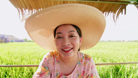 Beautiful-young-Asian-woman-with-hat-in-rice-field-making-video-call