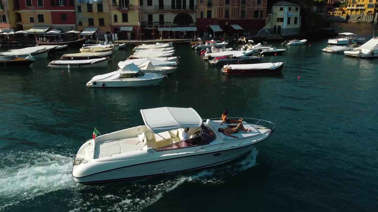 Vista aerea di persone che si rilassano sul ponte di una barca mentre navigano nel porto turistico di Portofino, in Italia.