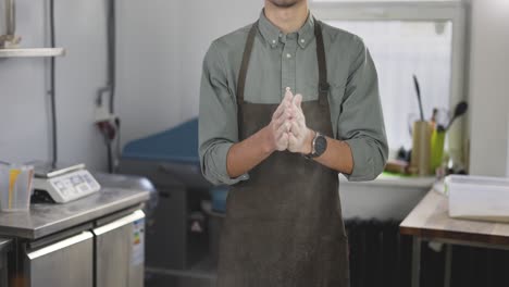 Handsome-male-baker-claps-and-scatters-white-flour-in-the-air.-Young-man-making-homemade-bread-claps-with-a-handful-of-organic