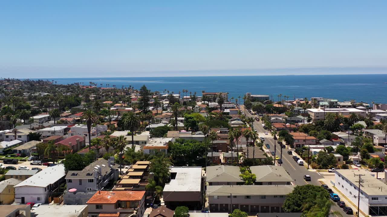 Drone stiger op over huse og palmer i Ocean Beach San Diego og bevæger sig mod kystlinjen og havet.