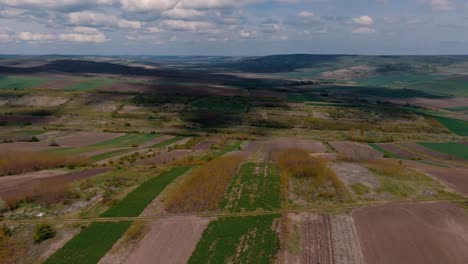 aerial view over agricultural fields, surrounding hills, partly cloudy