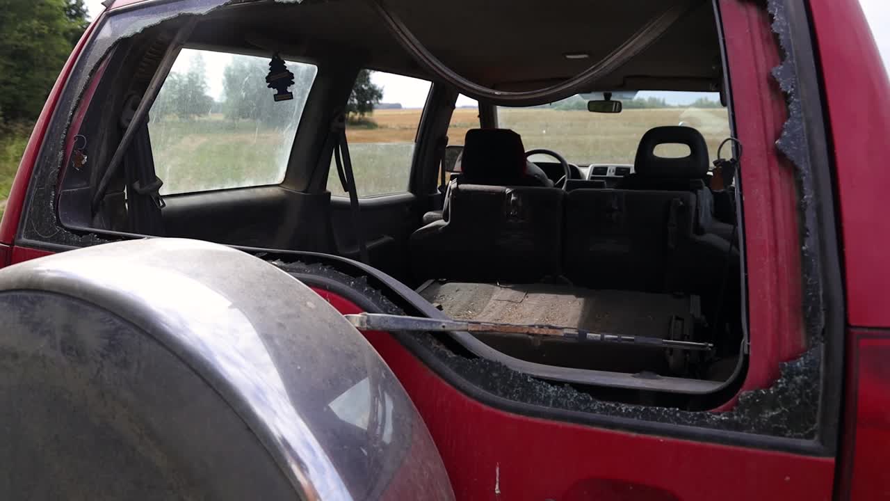 una vista a través de la ventana rota de la puerta trasera de los autos
