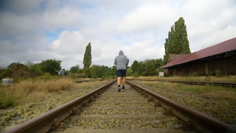 Back-View-Of-A-Sporty-Man-Running-On-Empty-Railroad