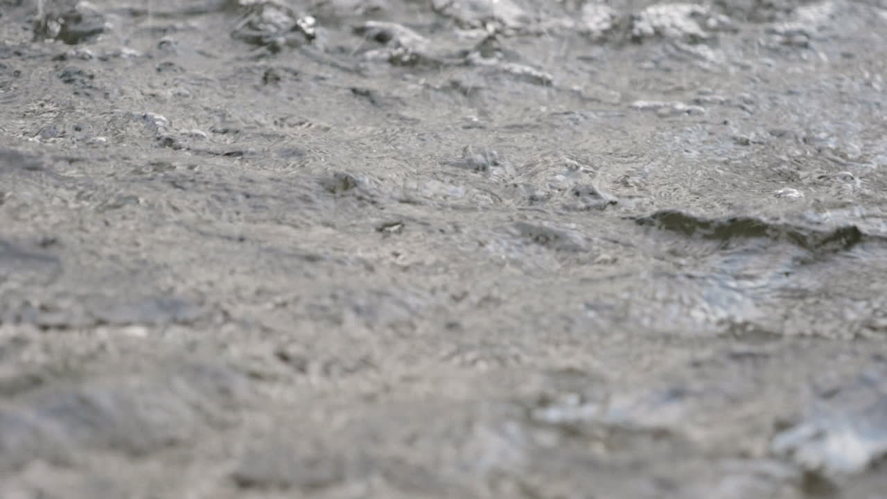 Detailed view of rippling water with small bubbles and surface textures, showcasing natural fluid motion and aquatic beauty. Slow Motion.
