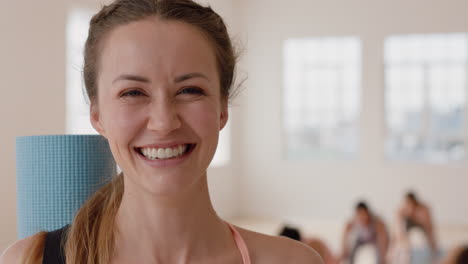 retrato hermosa mujer caucásica de yoga riendo feliz disfrutando de un estilo de vida saludable con gente practicando en el fondo del gimnasio
