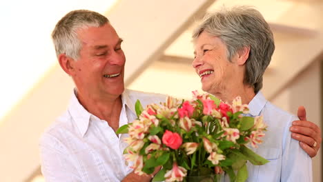 Senior-woman-smelling-bouquet-of-flowers-with-her-partner