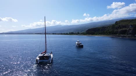 Drone-footage-of-a-catamaran-with-people-and-another-boat-near-a-cliff