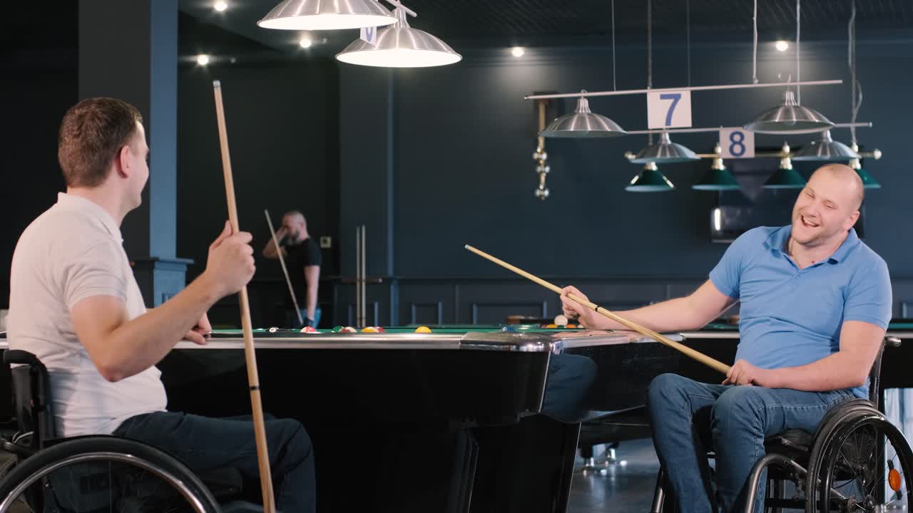 체어에 앉아 있는 장애인 성인 남성들이 클럽에서 빌리어드를 치고 있습니다.