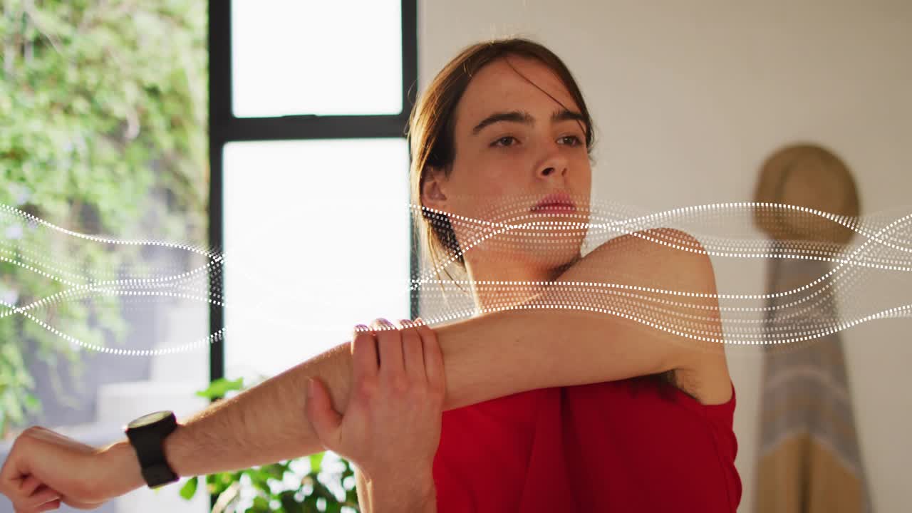 Frau hebt den rechten Arm, um eine Schulterdehnung zur Gesundheit im Heim-Fitnessstudio einzuleiten, während eine Wellenform pulsiert.