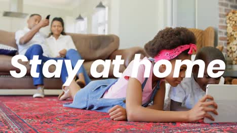 animation of stay at home text over parents with sister and brother using tablet at home