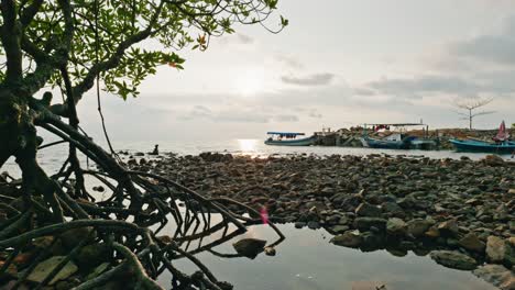 Barcos-De-Pesca-Tumbados-En-La-Playa-Pedregosa-Y-árida-De-La-Isla-Con-Nubes-Moviéndose-Por-Encima