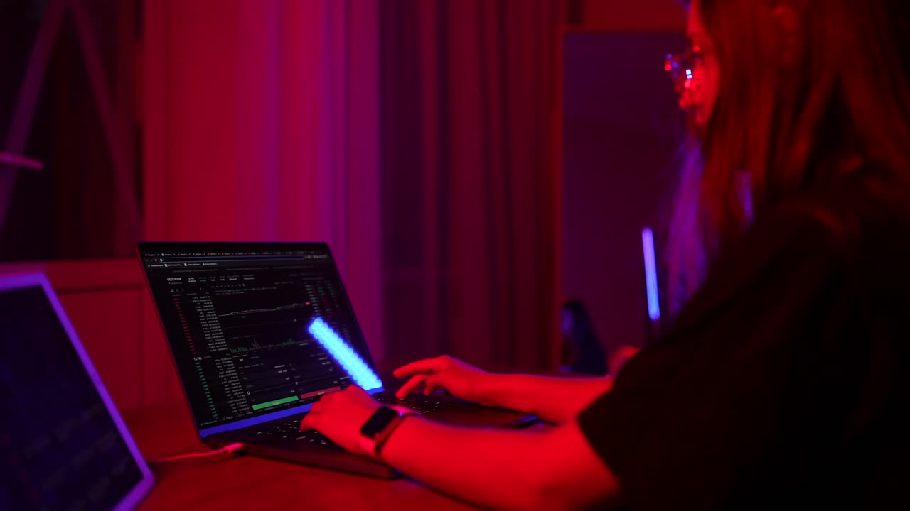 Person working on a laptop at night, analyzing financial data