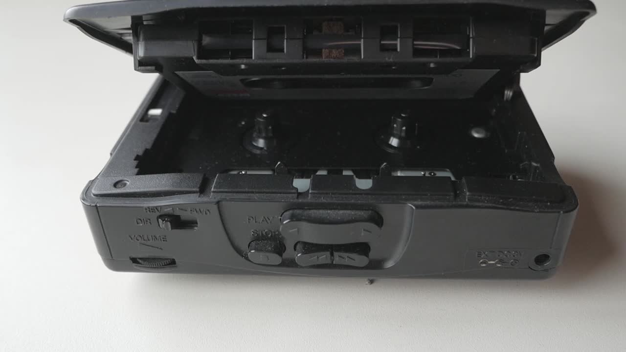 Walkman and cassette tape, hand pressing buttons to play music, close-up view of the controls