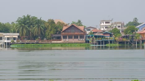 a tourist jet skiing and speeding through a river in thailand - wide shot