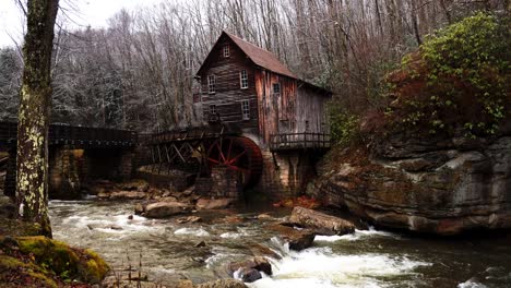 grist mill in west virginia with river flowing and snow falling