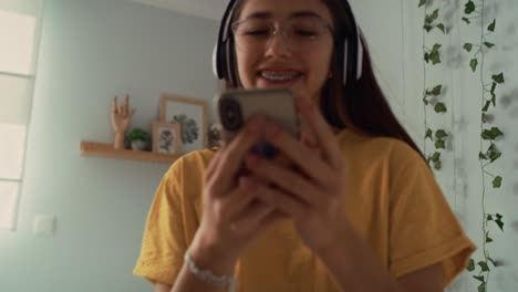 Caucasian-teenage-girl-dancing-in-her-room-with-headphones-and-phone