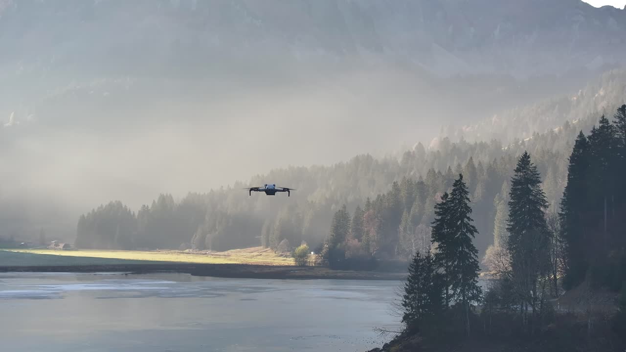 단독 드론이 스위스의 오버시 호수 위를 날아다니며 안개 숲과 조용한 물에 둘러싸여 평온한 알프스 환경에서 기술과 자연을 혼합합니다.
