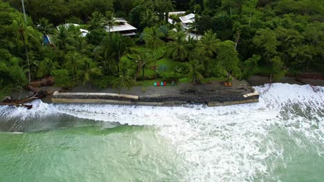 drone ascends from pacific shoreline in costa rica where two women are standing near the water’s edge