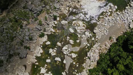 a distant aerial shot moves forward, revealing the river amid rocks and surrounding nature at tinipak river, philippines