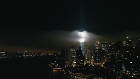 Una-Vista-Aérea-De-La-Torre-De-La-Libertad-En-La-Ciudad-De-Nueva-York-Por-La-Noche,-Con-El-Homenaje-En-Haces-Gemelos-Iluminados