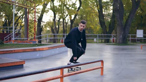 extreme skateboarder listening to the music in earphones grinding down rail in the skatepark. slow motion shot