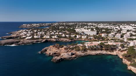 Vista-Aérea-Con-Drones-Viendo-El-Pueblo-De-Cala-D&#39;or-Con-Casas-Blancas,-Acantilados-Y-El-Mar-Mediterráneo