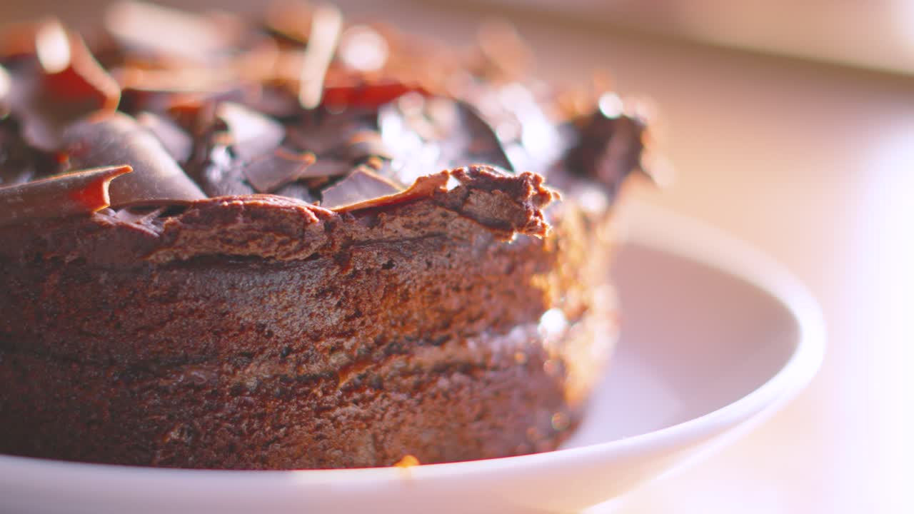 Close Up of Milk Chocolate Cake Dessert in Natural Lighting with Sun Flare. Details of Middle Frosting and Smooth Topping. Served at Birthday Parties or Afternoon Tea. Food Photography.