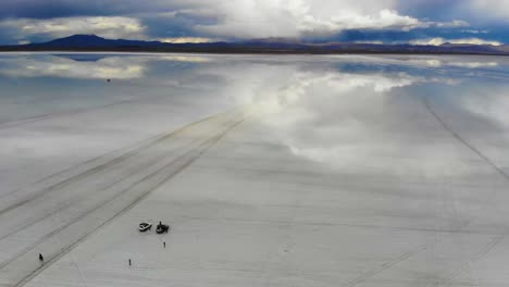 Antenne-Von-Menschen,-Die-Sich-Auf-Dem-Uyuni-Salzsee-Mit-Perfekten-Reflexionen-In-Bolivien-Versammeln-1