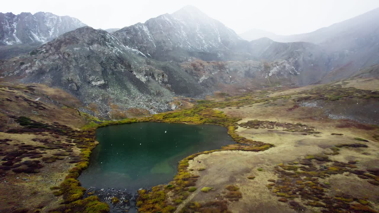 Hermoso lago en las montañas de Colorado durante una tormenta de granizo con excursionistas a lo largo del sendero de montaña
