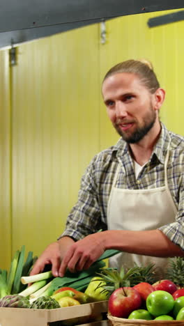 male staff assisting woman in selecting fresh vegetables