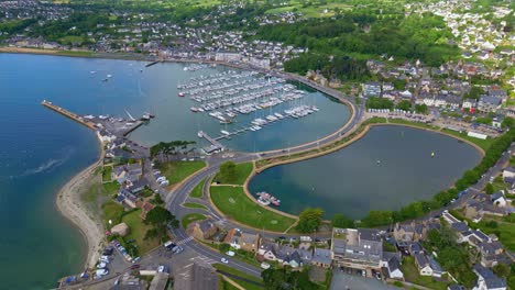 perros-guirec harbor with sailboats, coastal town, causeway, and green countryside, brittany, france. aerial drone forward