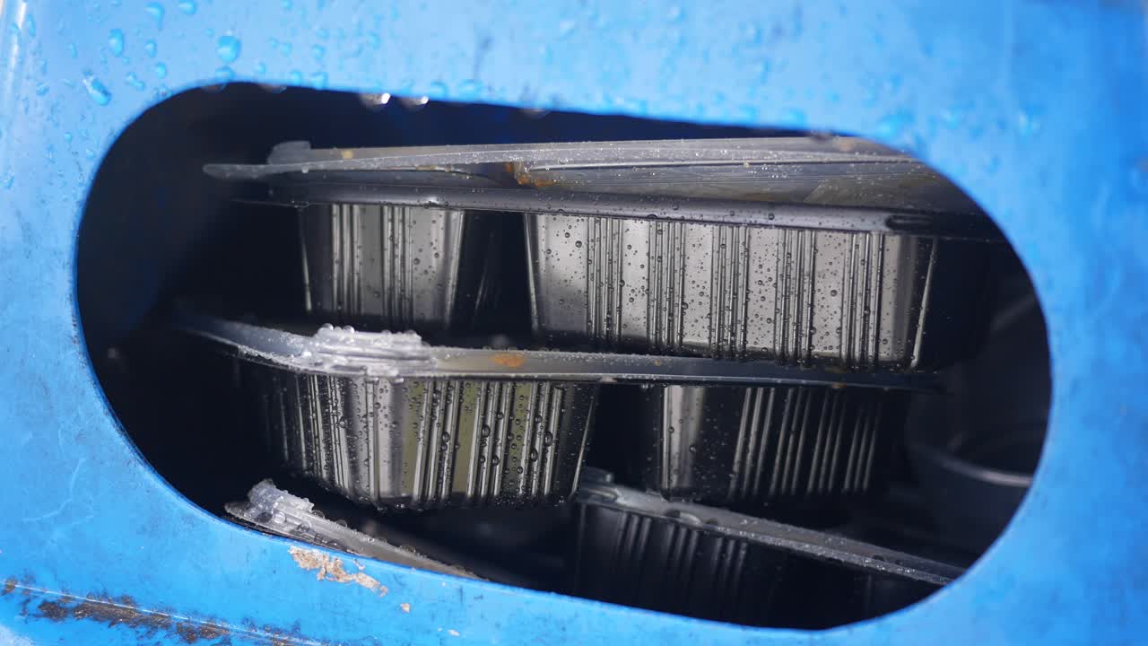 contenedores de alimentos empapados de lluvia en un contenedor azul