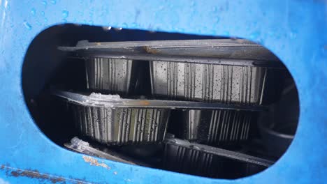 rain-soaked food containers in a blue bin