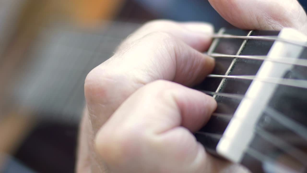 Extreme close up of healthy aging fingers playing chords on guitar
