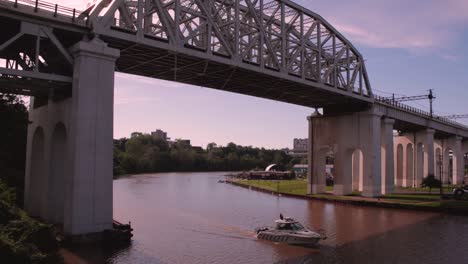 the cuyahoga river around dusk where a boat passes under a train trestle bridge