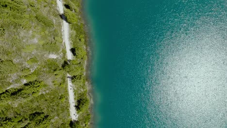 aerial drone shot of the river with boats and path in the pine forest, lago di braies, italy, dolomites