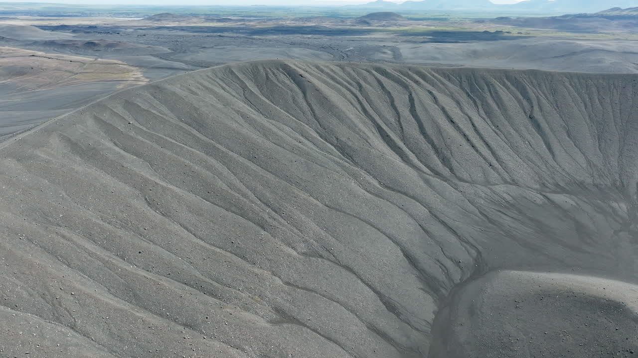 cráter del volcán con arena negra y paisaje escénico en el fondo, aérea