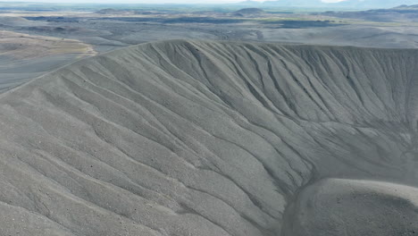 cráter del volcán con arena negra y paisaje escénico en el fondo, aérea