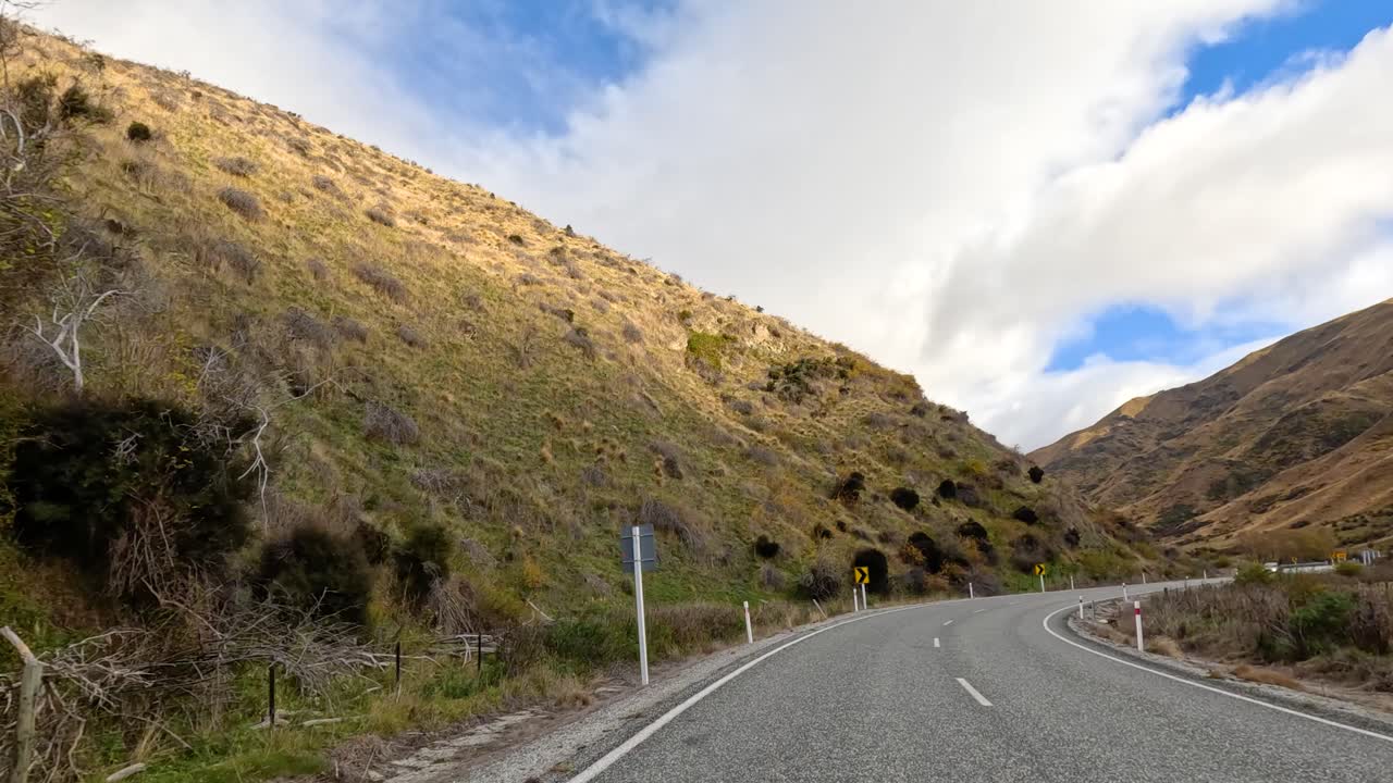 A picturesque drive through Wanaka's winding mountain roads, showcasing stunning landscapes under clear skies and dynamic lighting