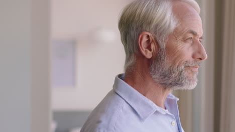 portrait happy old man drinking coffee at home looking out window smiling enjoying retirement lifestyle planning ahead