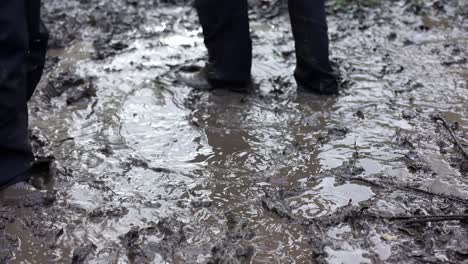 Dos-Niños-Pequeños-Jugando-En-Un-Charco-De-Barro,-Vestidos-Con-Ropa-Impermeable