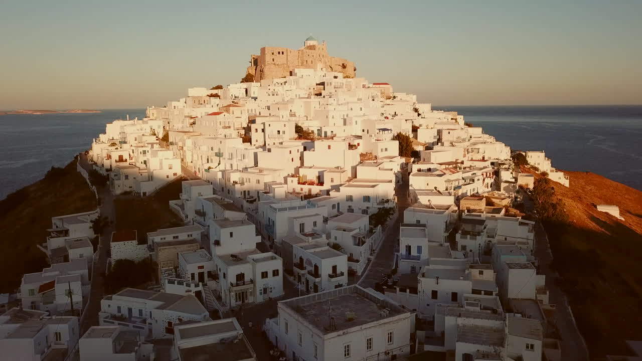 Castle of Astypalea,4K aerial footage of Querini Castle during golden hour.Drone footage zooms from windmills of Astypalea through to the beautiful castle where the blue dome of the church is visible