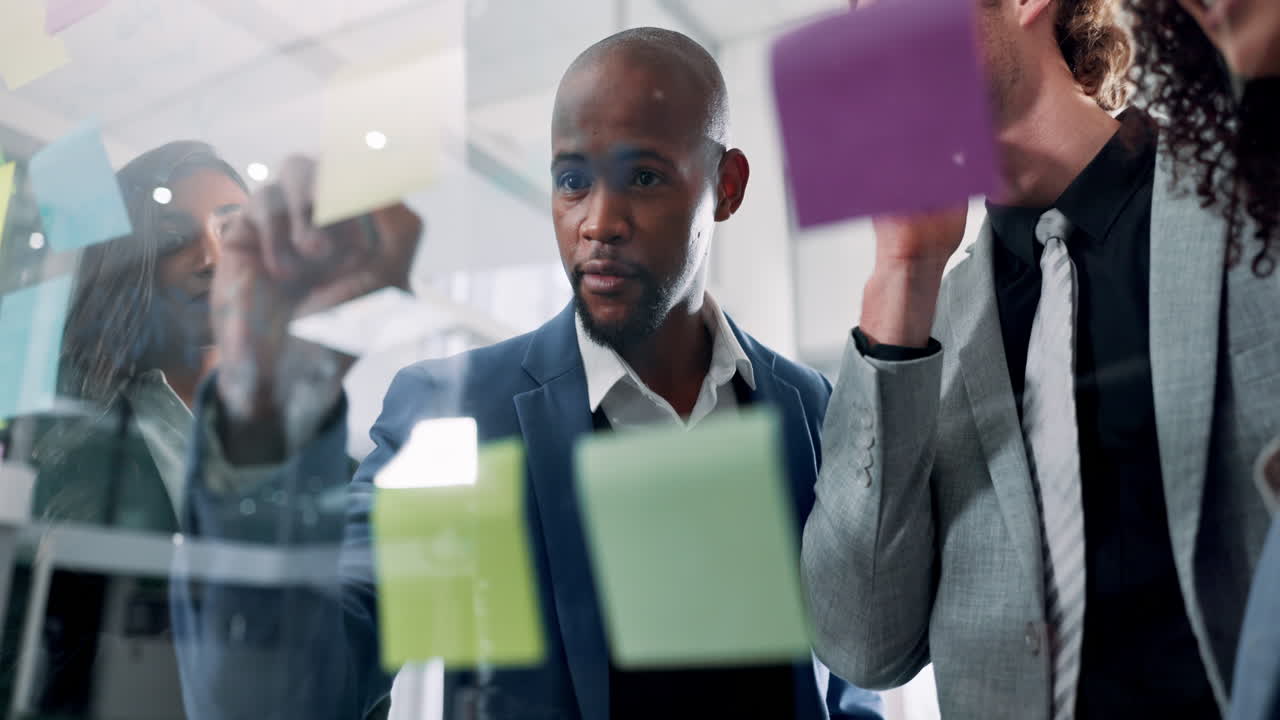 Business team brainstorming and planning with sticky notes on a glass wall