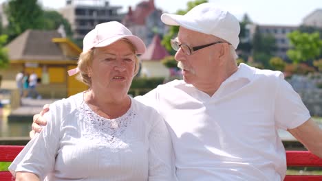 elderly couple talking on a bench in a park